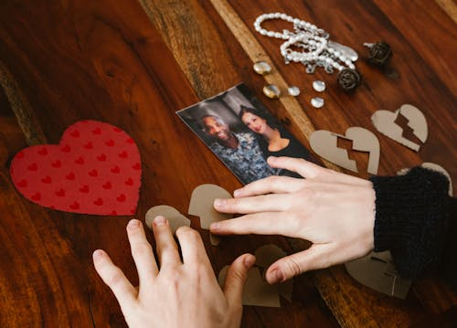 A woman arranging broken hearts near a couple of pictures