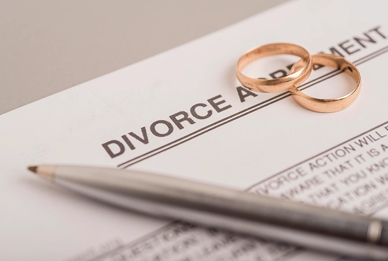 Divorce papers are placed on the desk with a pen and rings.