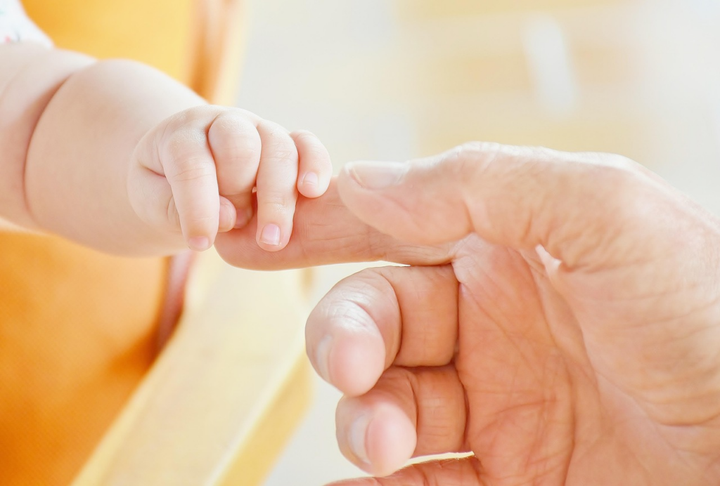 close-up of a baby’s and an adult’s hands touching