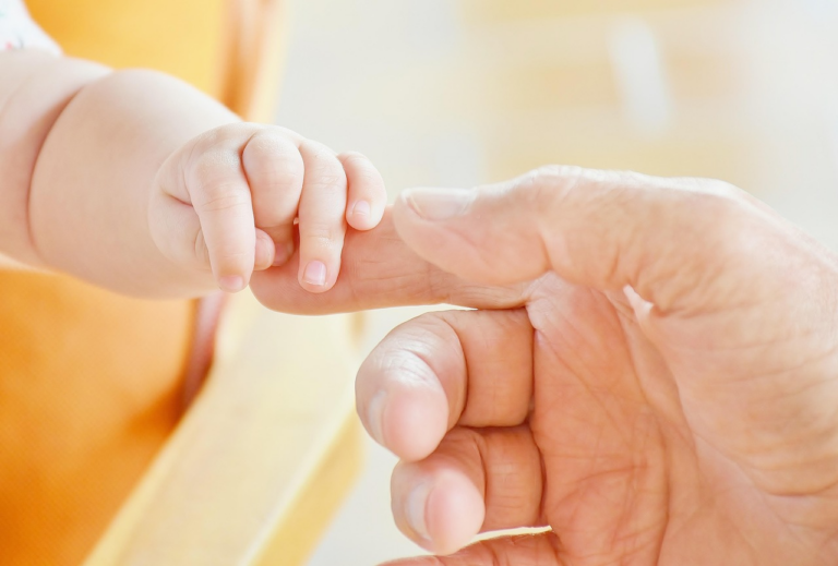 close-up of a baby’s and an adult’s hands touching