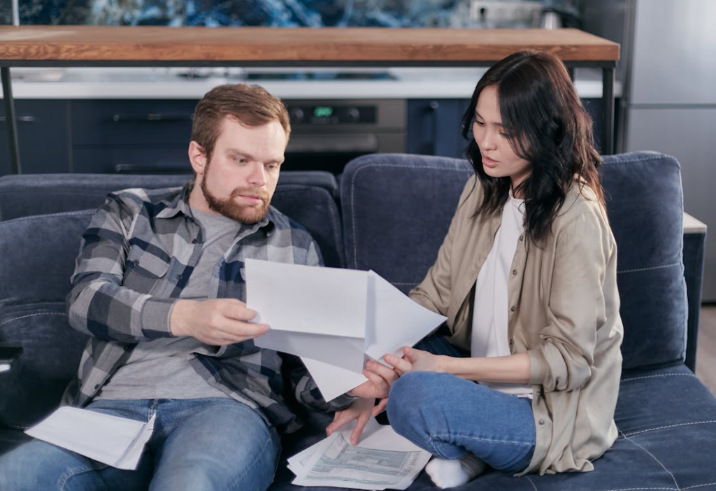 A couple sitting apart reviewing financial documents during a tense discussion