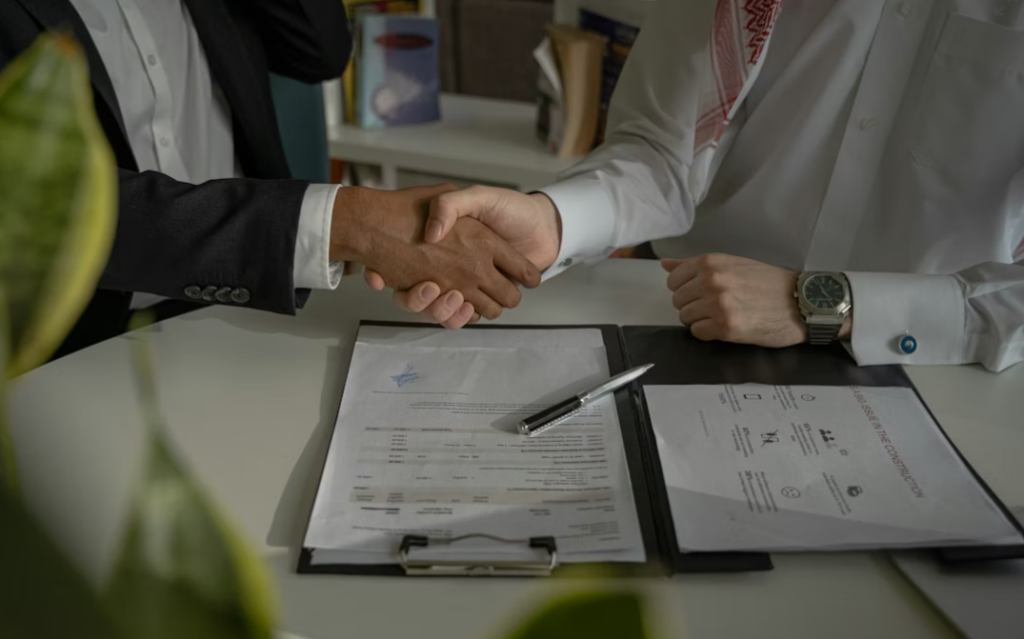 This image shows two people shaking hands over a piece of paper.