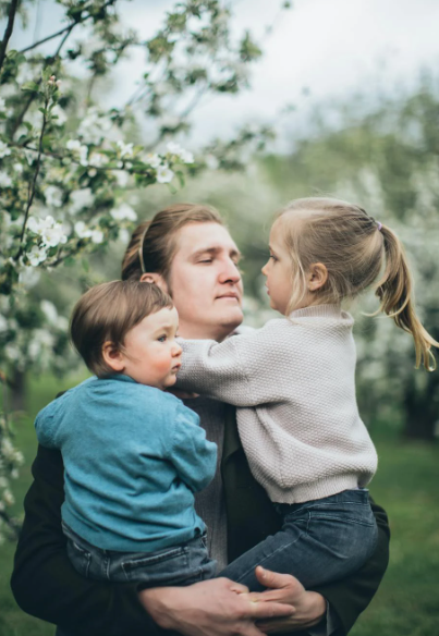 This image shows a father with his children at a park.