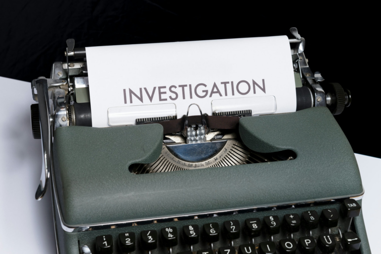 A typewriter has paper on which the word “investigation” is written.