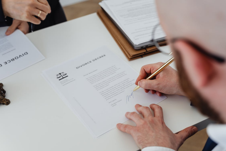A person signing legal documents on a desk with a pen