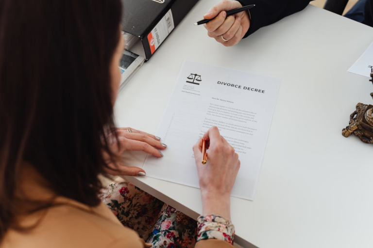 A woman holding a pen and signing a legal document on a desk