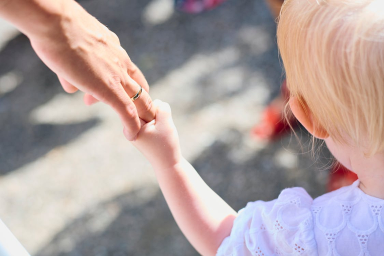 A child holding their parent’s hand