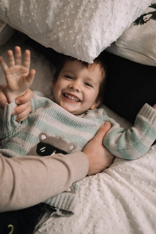 A child smiling at the camera with a parent.