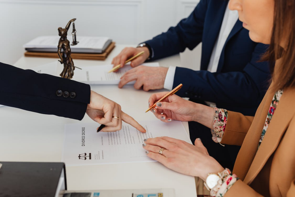 Attorneys and clients reviewing a divorce agreement document during a legal consultation.