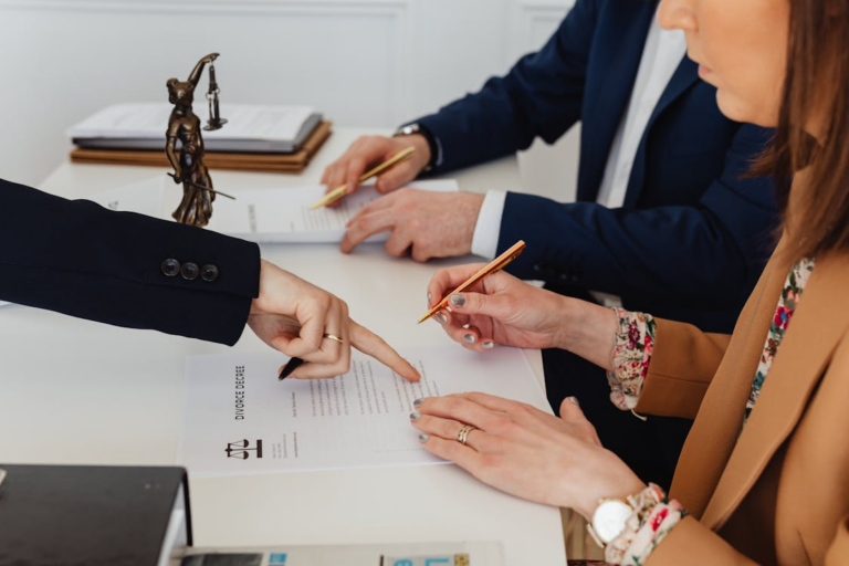 Attorneys and clients reviewing a divorce agreement document during a legal consultation.