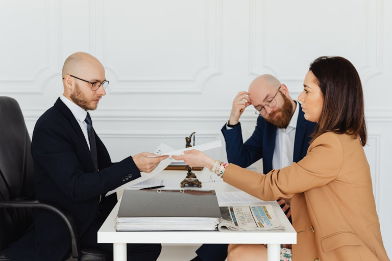 High-net-worth couple meeting with a divorce attorney in a modern office while reviewing financial documents.