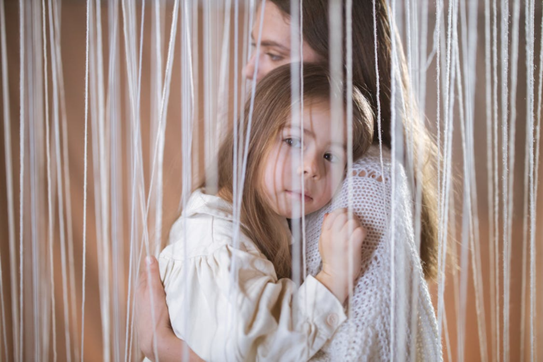a mother embracing her daughter behind a curtain
