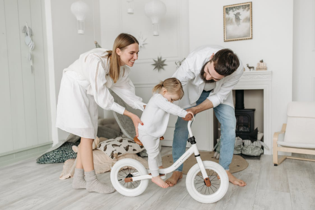 Two parents helping a child ride a bike