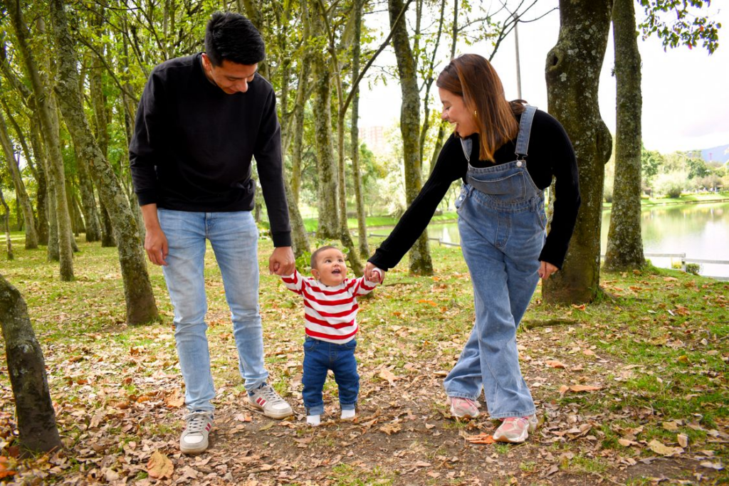 Parents holding the hands of their child in a park