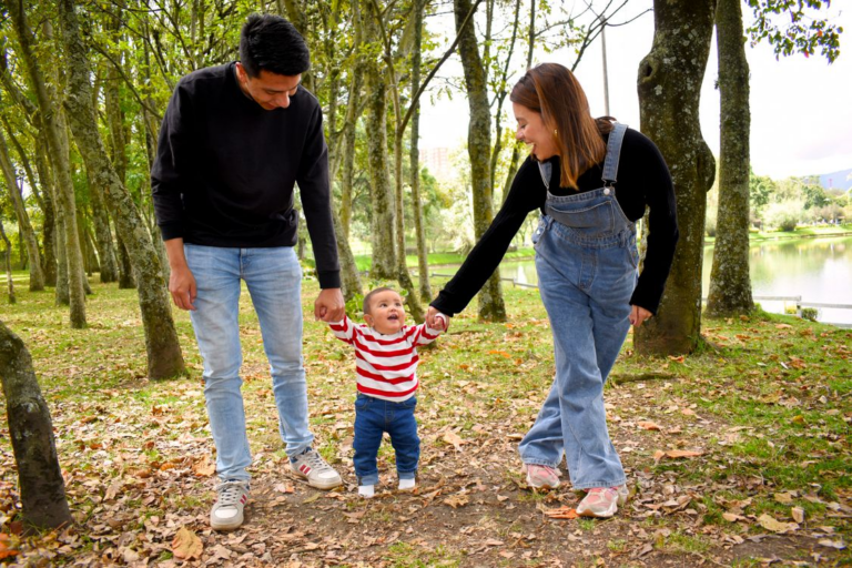 Parents holding the hands of their child in a park
