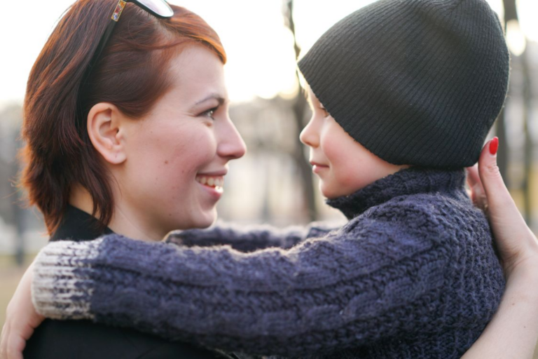 a mother carrying her son in her arms and smiling
