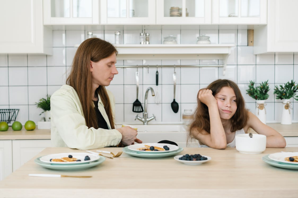 A parent and child sitting on the kitchen countertop with food