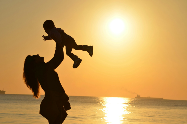 A mother with her baby on the beach during sunset