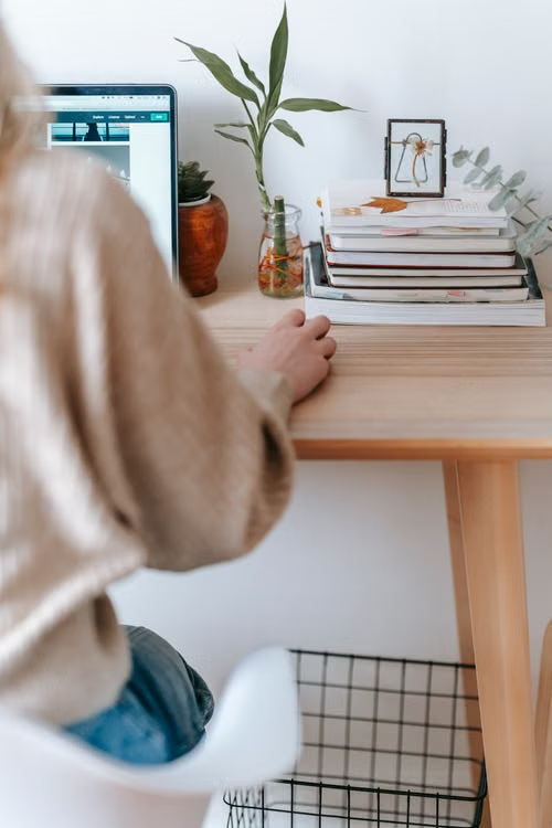 This image shows a person working on a laptop at a home table.