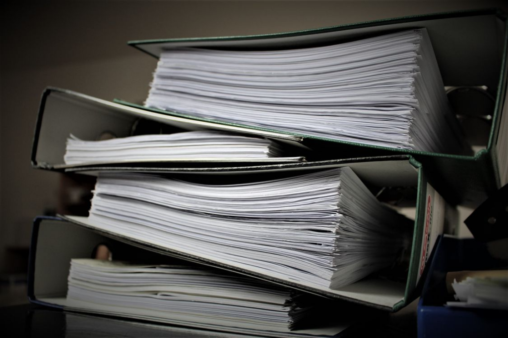 This image shows a stack of binders and folders filled with documents.
