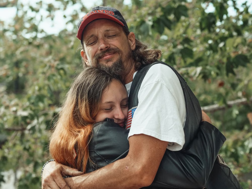 This image shows a father and daughter hugging outdoors.