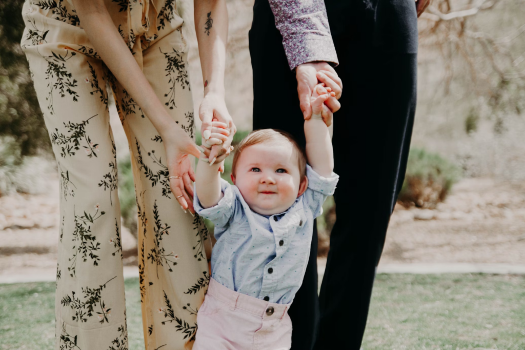 A toddler holding parents' hands