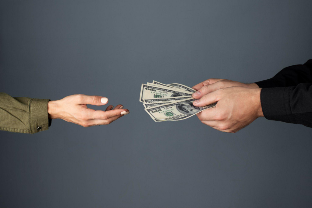 A person giving money to another person