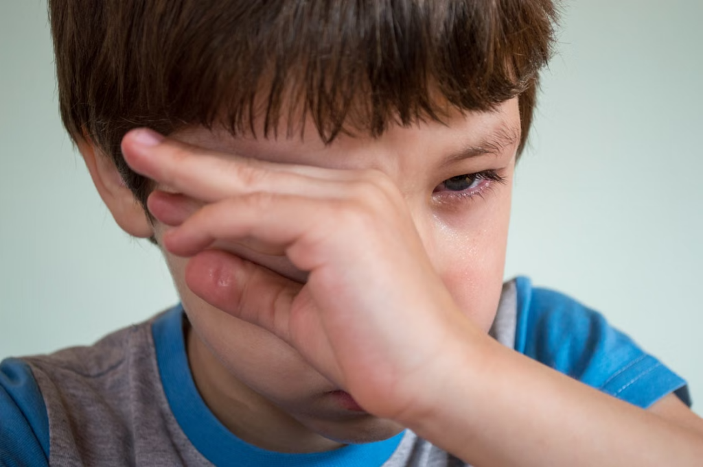 close-up of a little boy crying and wiping his tears