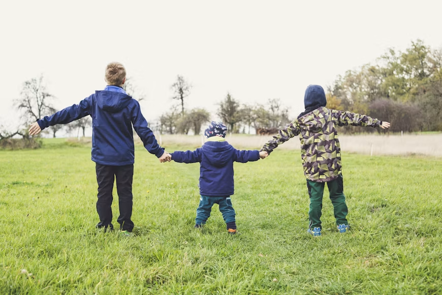 Three children standing together in a garden.