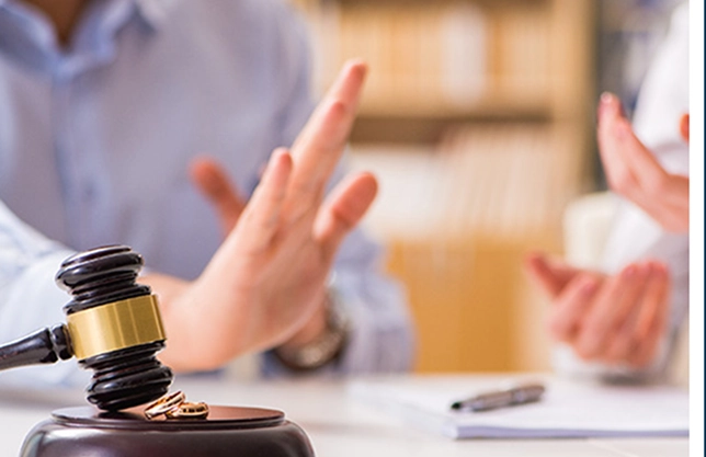 A wooden gavel and two rings in front of a couple