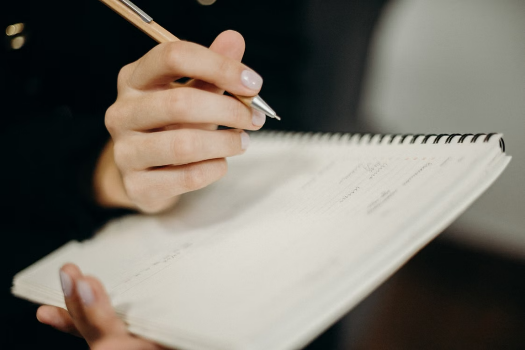 A person writing in a notebook representing preparation for a contested divorce