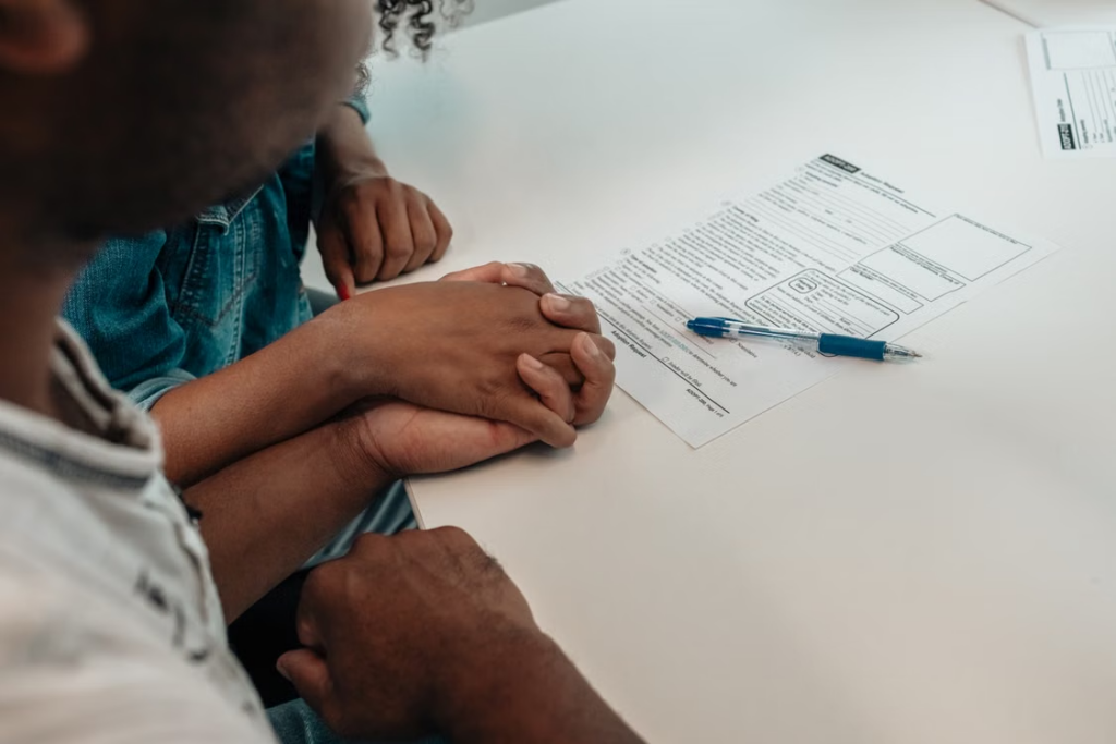 This photo shows a couple holding hands with a document in front of them.