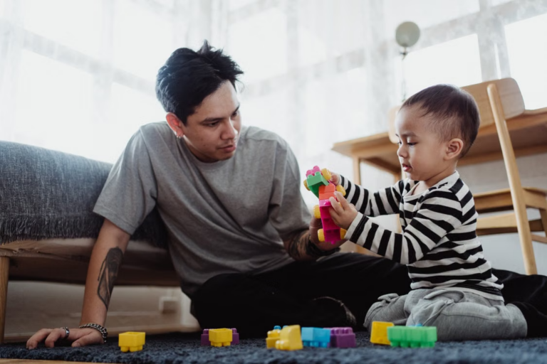 a father playing with building blocks with his son on the floor