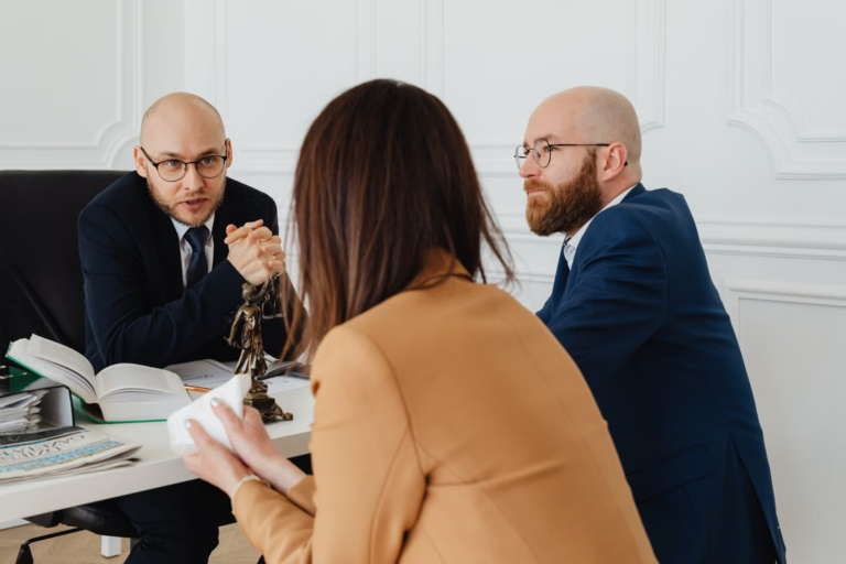 Two male attorneys sitting at a desk and discussing legal matters with a woman during a family law consultation.