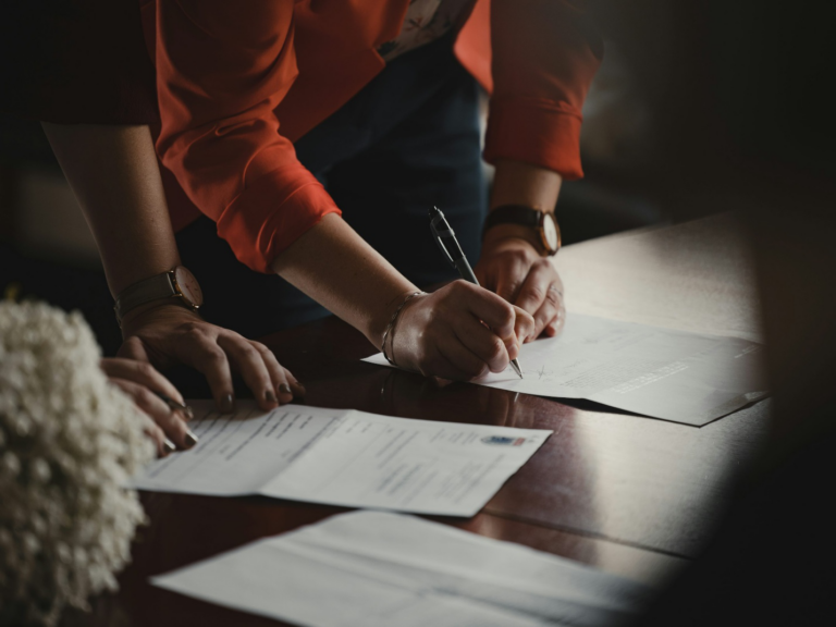 Person signing legal documents while preparing a prenuptial agreement in Piney Point Village.