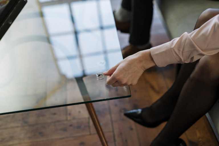 a woman's hand with a full-sleeved shirt putting her ring on a table